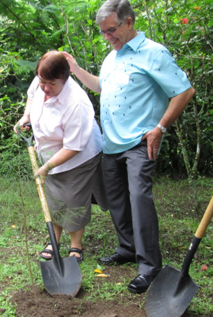 Mrs. Chris Tweddell taking her turn at the spade as the Ambassador cheers her efforts.